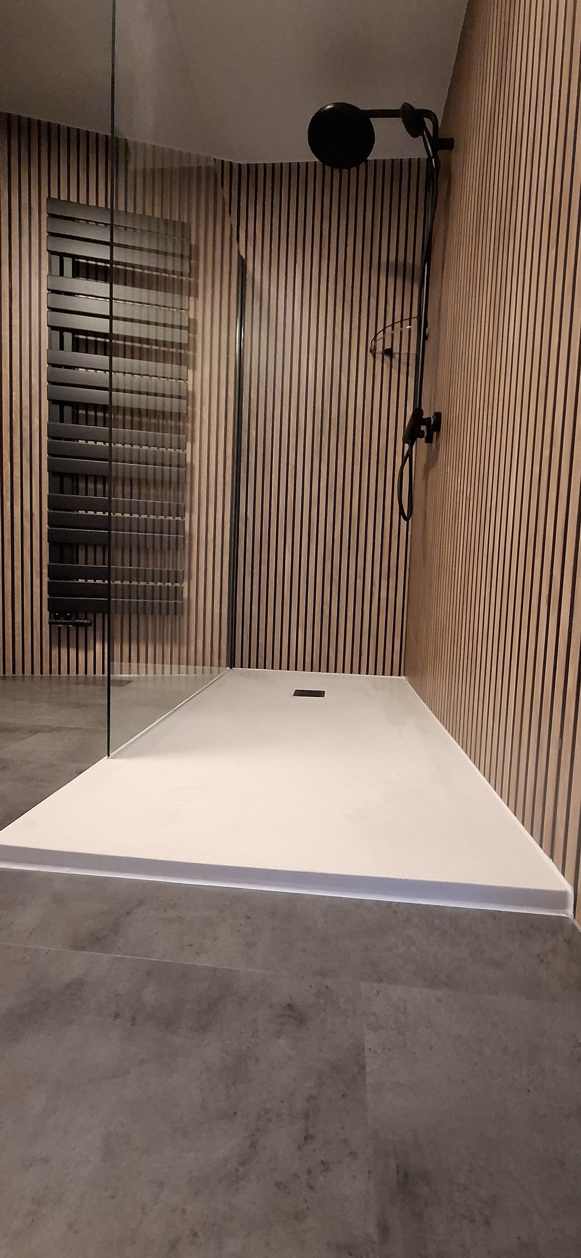 Stijlvolle inloopdouche met houtlook wandbekleding en zwarte details